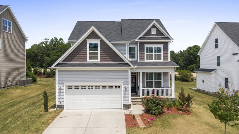 Aerial view of a modern suburban house in Fuquay-Varina with a well-maintained lawn and driveway featuring a vinyl garage door.