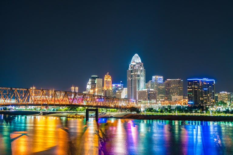 Captivating view of Cincinnati skyline with bridge reflections on Ohio River at night.