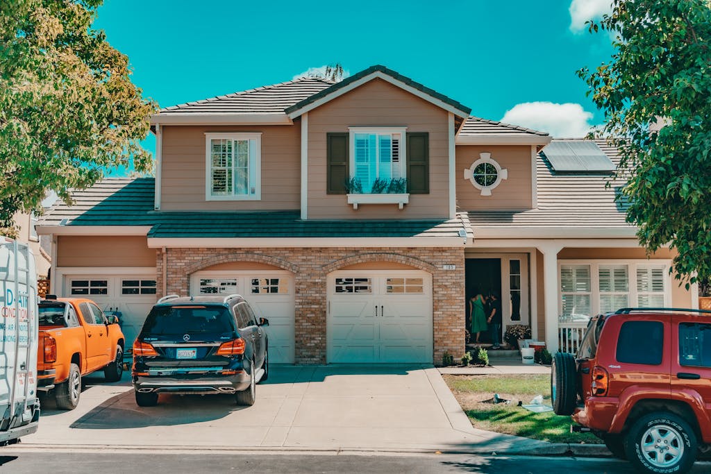 Charming suburban house with parked cars in front of aluminum garage doors