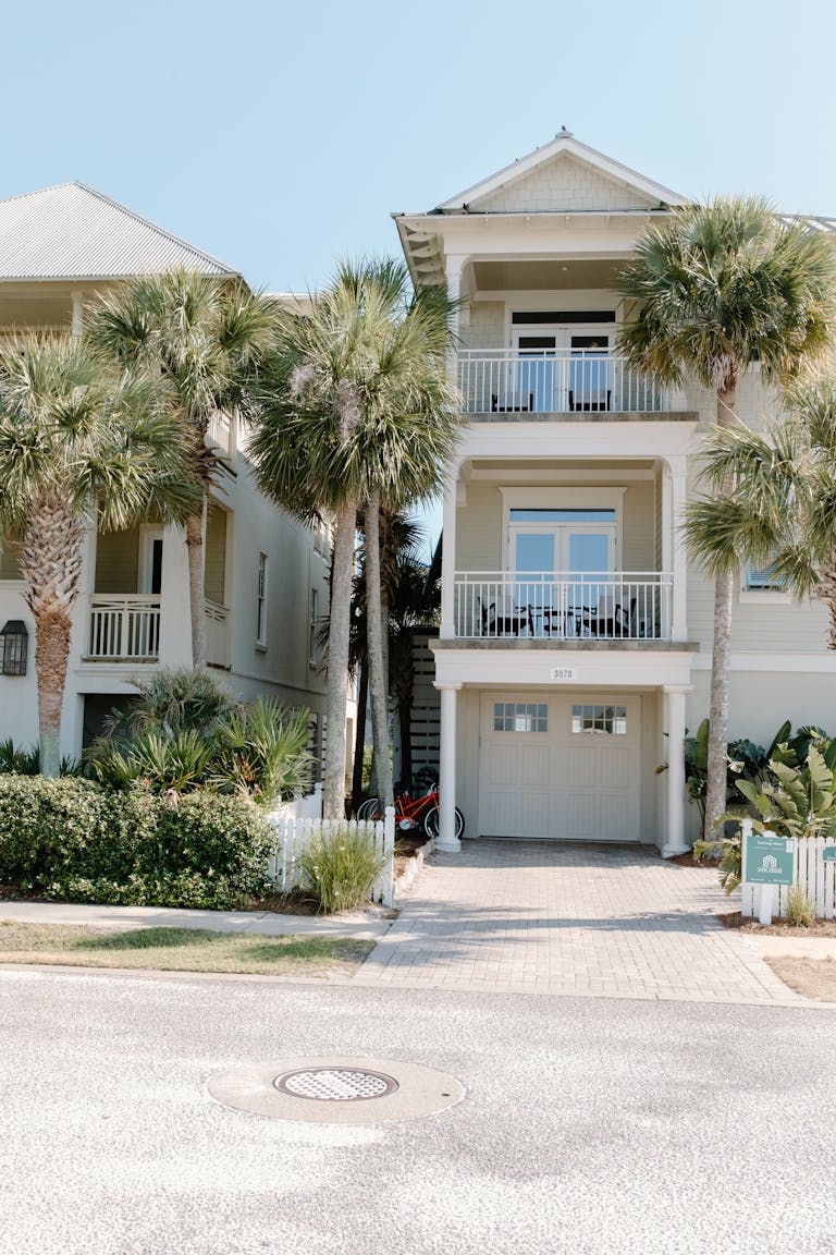 Charming three-story house with palm trees, and a fiberglass garage door, ideal beachside living.