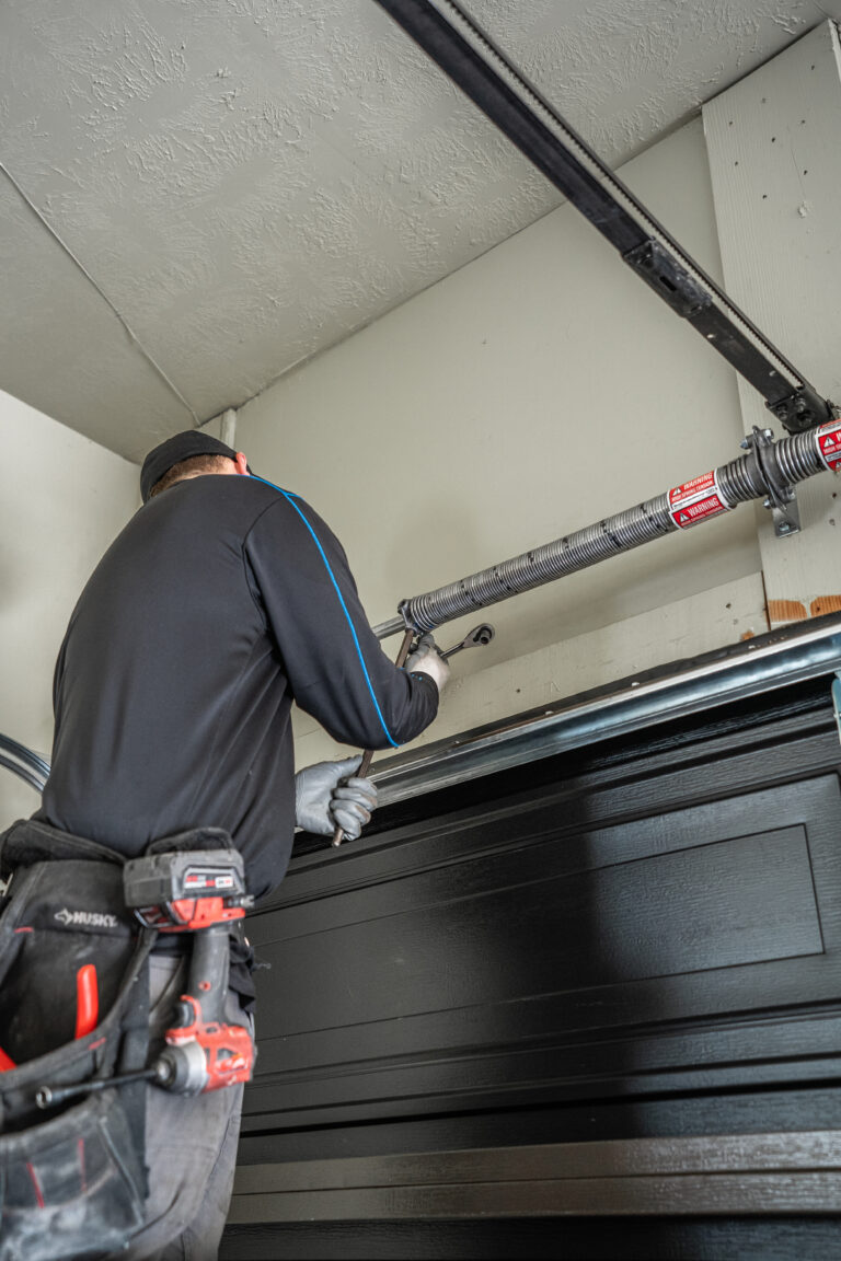 garage door repairman working on springs and cable replacement