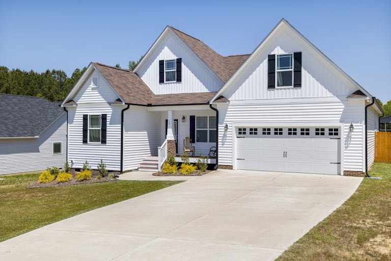 Elegant modern suburban home with garage and landscaped garden in daylight.
