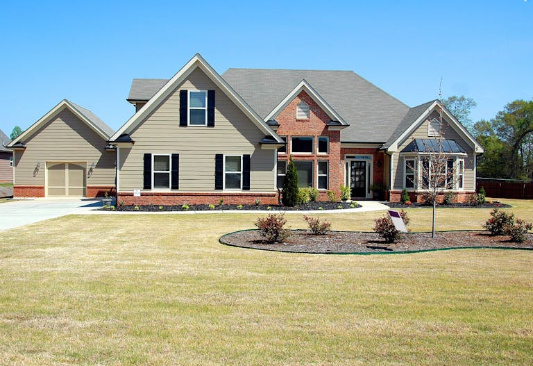 Elegant suburban family house with large lawn and driveway, featuring sliding carriage style garage doors