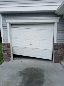 Garage door shown in need of repair, off track, will not close