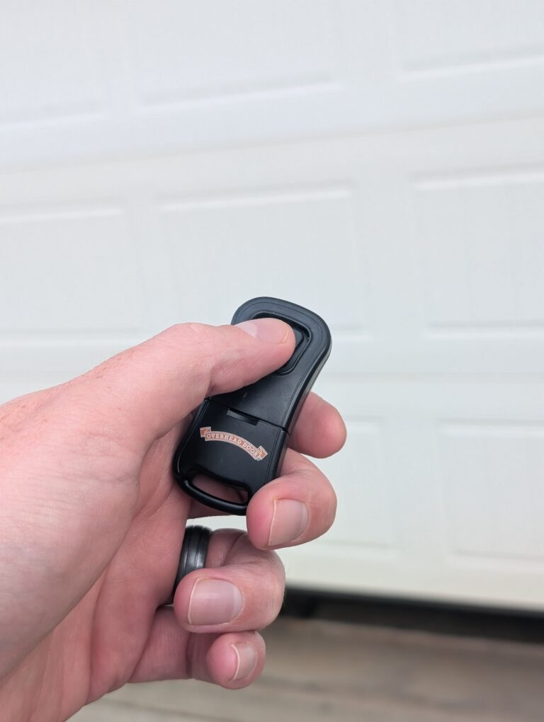 Homeowner opening garage with remote garage door opener form driveway
