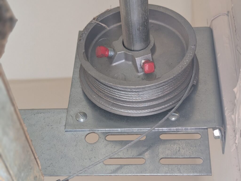 Garage cble roll in action while torsion spring pulls cables to open door.