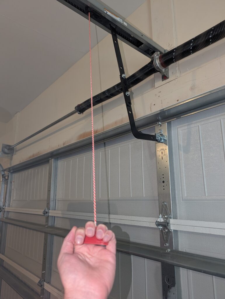 Homeowner pulling manual garage door release cord in order to operate garage door manually without power or automatic opener.