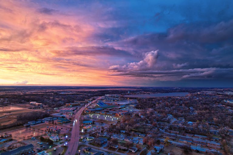 Stunning aerial view of Stillwater, Oklahoma, showcasing vibrant skies at sunset with urban cityscape below.