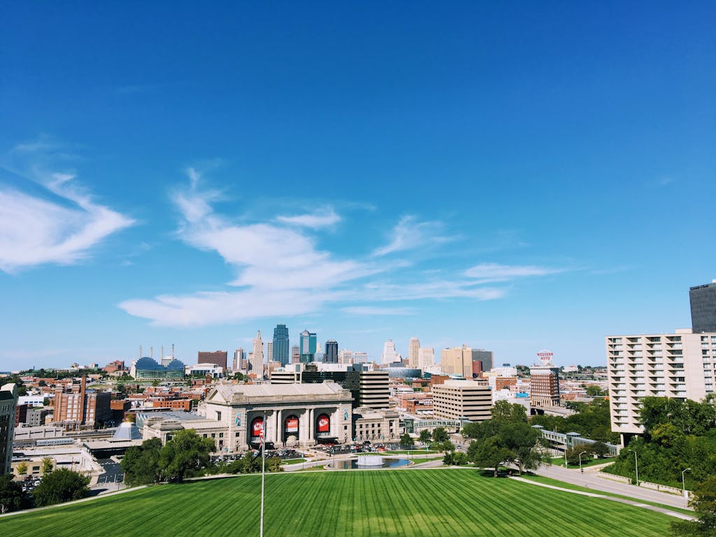 Wide-angle shot of Kansas City's skyline with clear blue skies and vibrant green foreground.