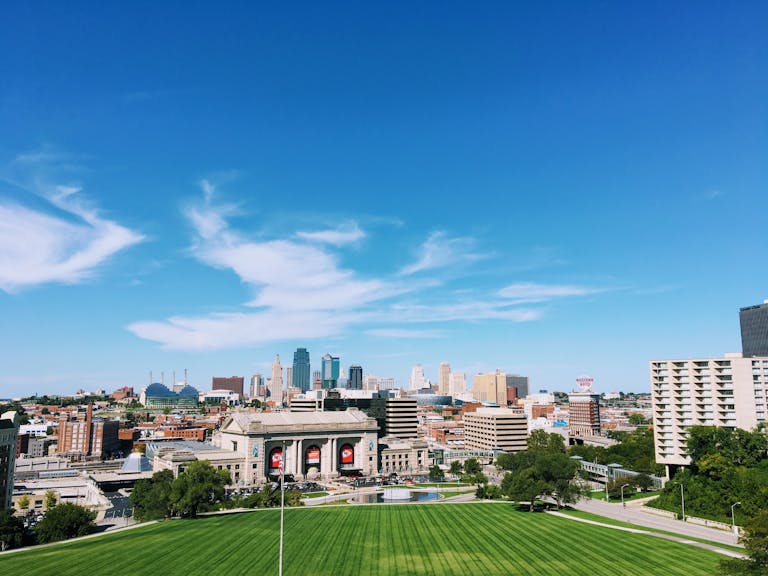 Wide-angle shot of Kansas City's skyline with clear blue skies and vibrant green foreground.